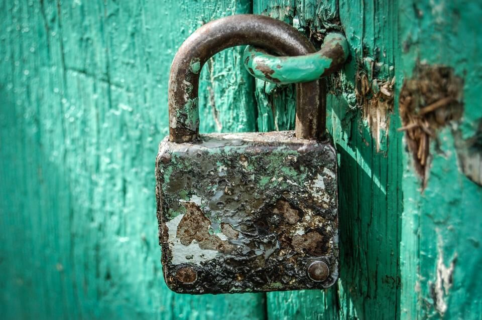 An old rusty padlock securing a wooden barn door