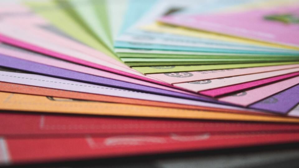A fan of brightly coloured paper samples spread across a desk