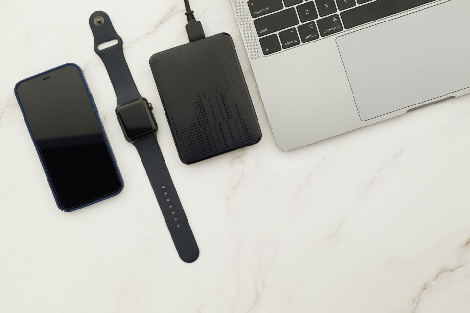 Top-down view of a tidy desk with laptop, phone, smartwatch and hard drive
